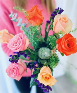 Energigivande blombukett med rosa, orange och aprikosa rosor tillsammans med statice och dekorationsgrönt. Du hittar blommorna hos Made4y.se.